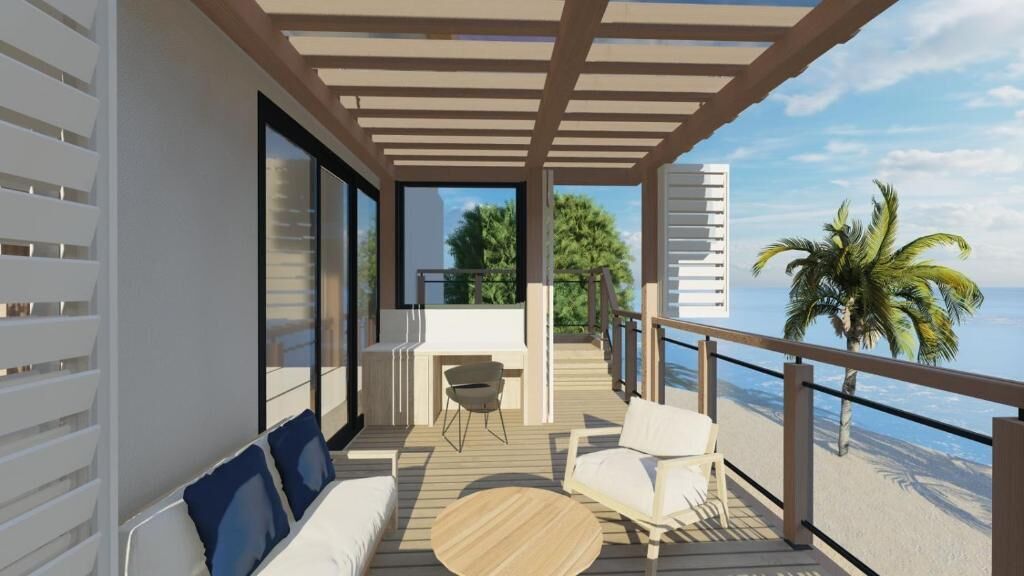 A balcony with a wooden floor, white furniture, and a view of the beach.