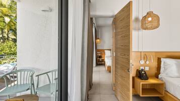 Una moderna camera d'albergo con un letto di legno, un comodino con il telefono e vista sul balcone.
