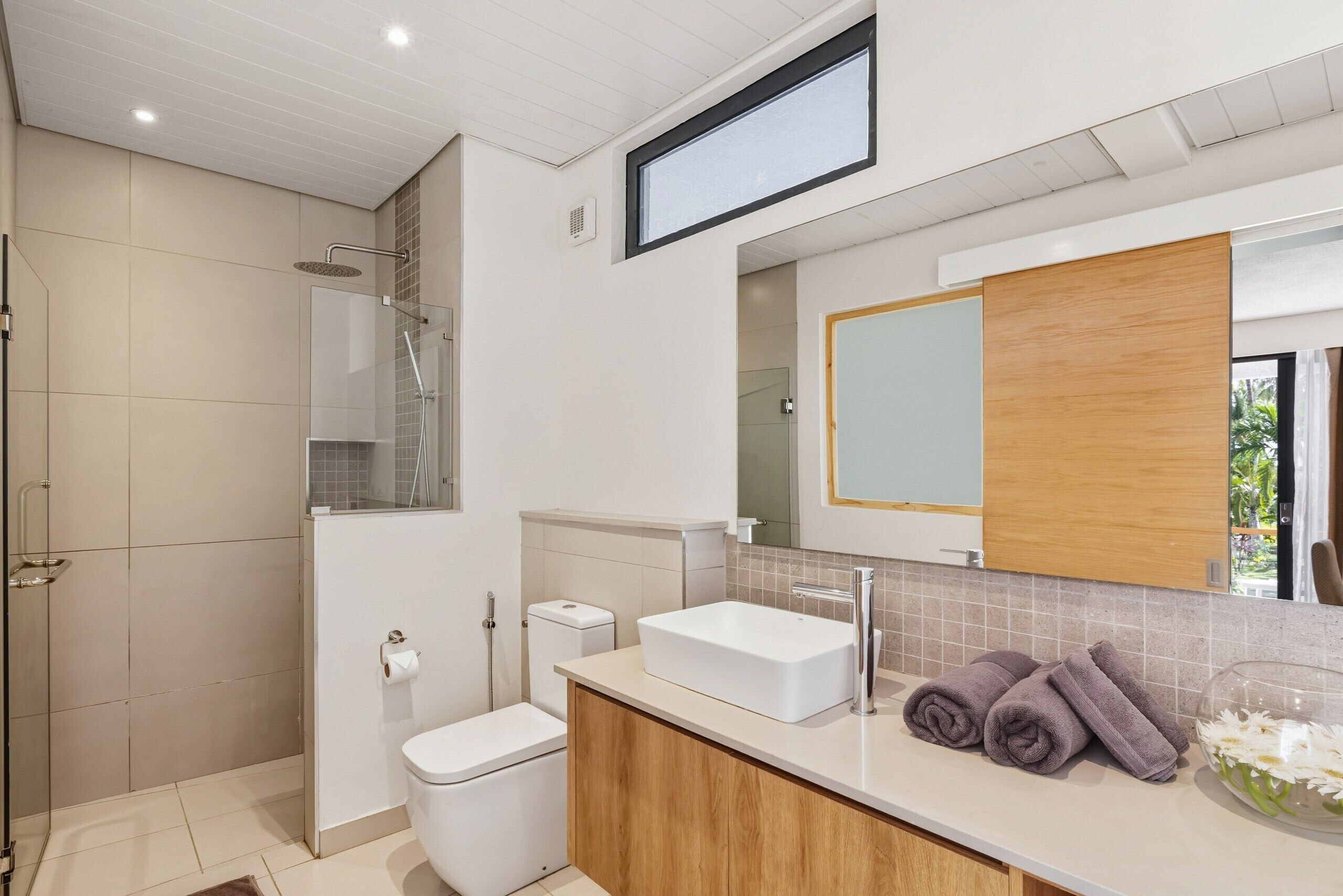 Une salle de bain moderne équipée d’une douche, de toilettes, d’un lavabo et d’un meuble-vasque.