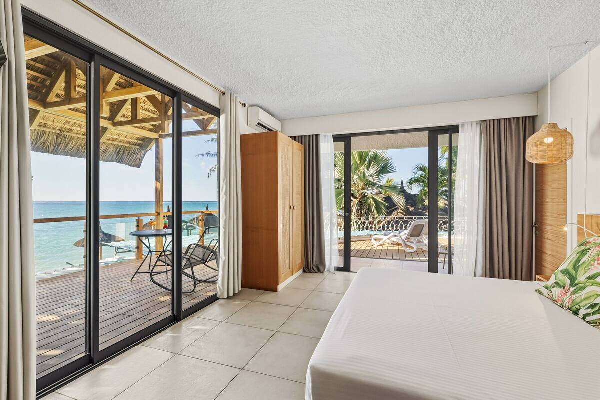 Habitación de hotel con cama, balcón y vistas al mar, además de una zona de piscina.