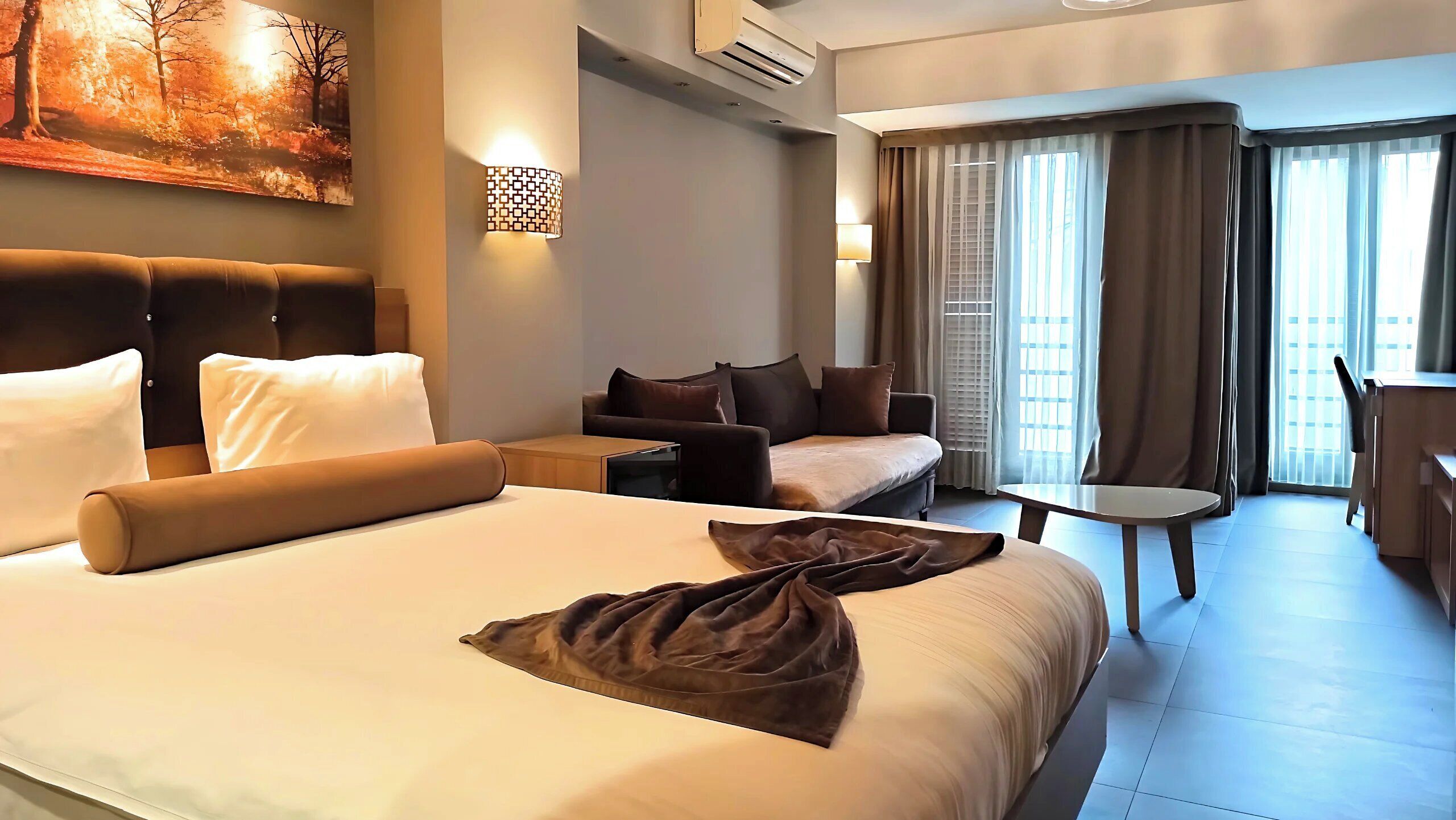 Une chambre d’hôtel avec un grand lit, un canapé, une petite table et un bureau.