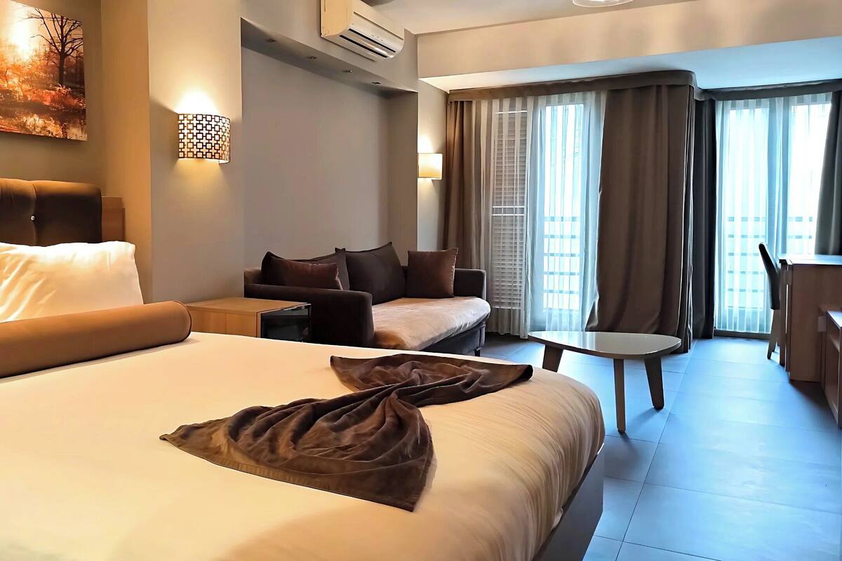 Une chambre d’hôtel avec un grand lit, un canapé, une petite table et un bureau.