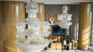 A lobby with a large, ornate chandelier and a reception desk. - Grand Hotel (Salmiya)
