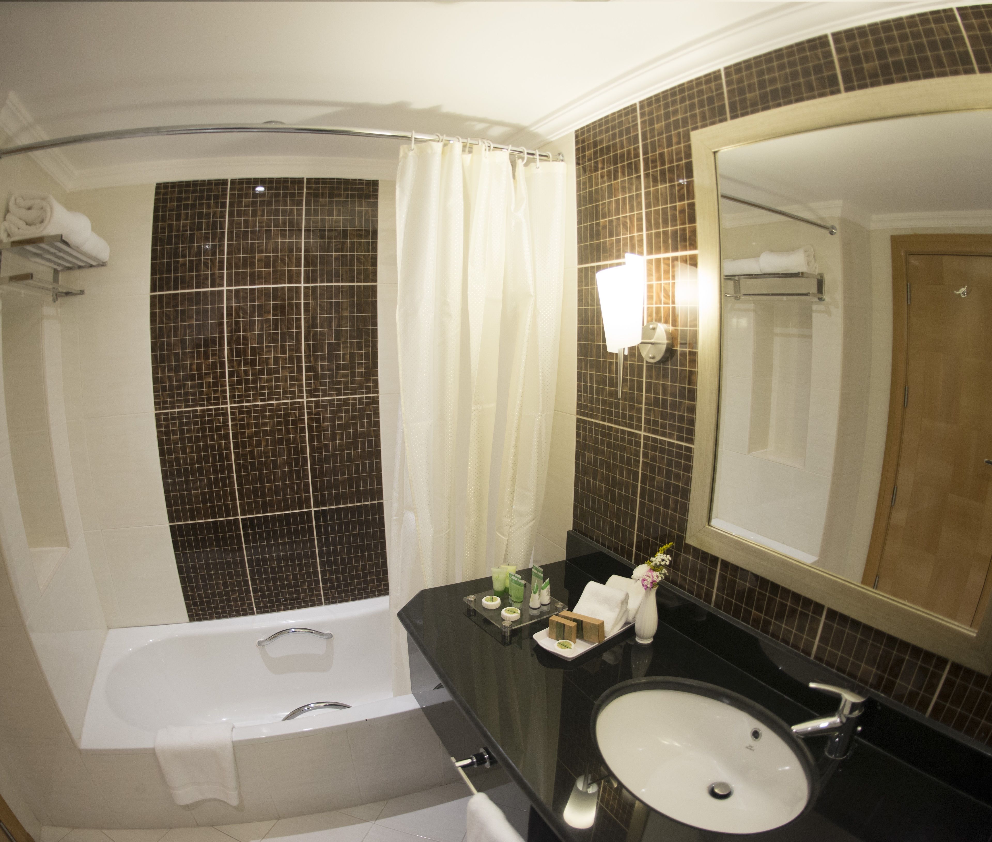 Une salle de bain équipée d’une baignoire, d’un lavabo, d’un miroir et d’un rideau de douche.