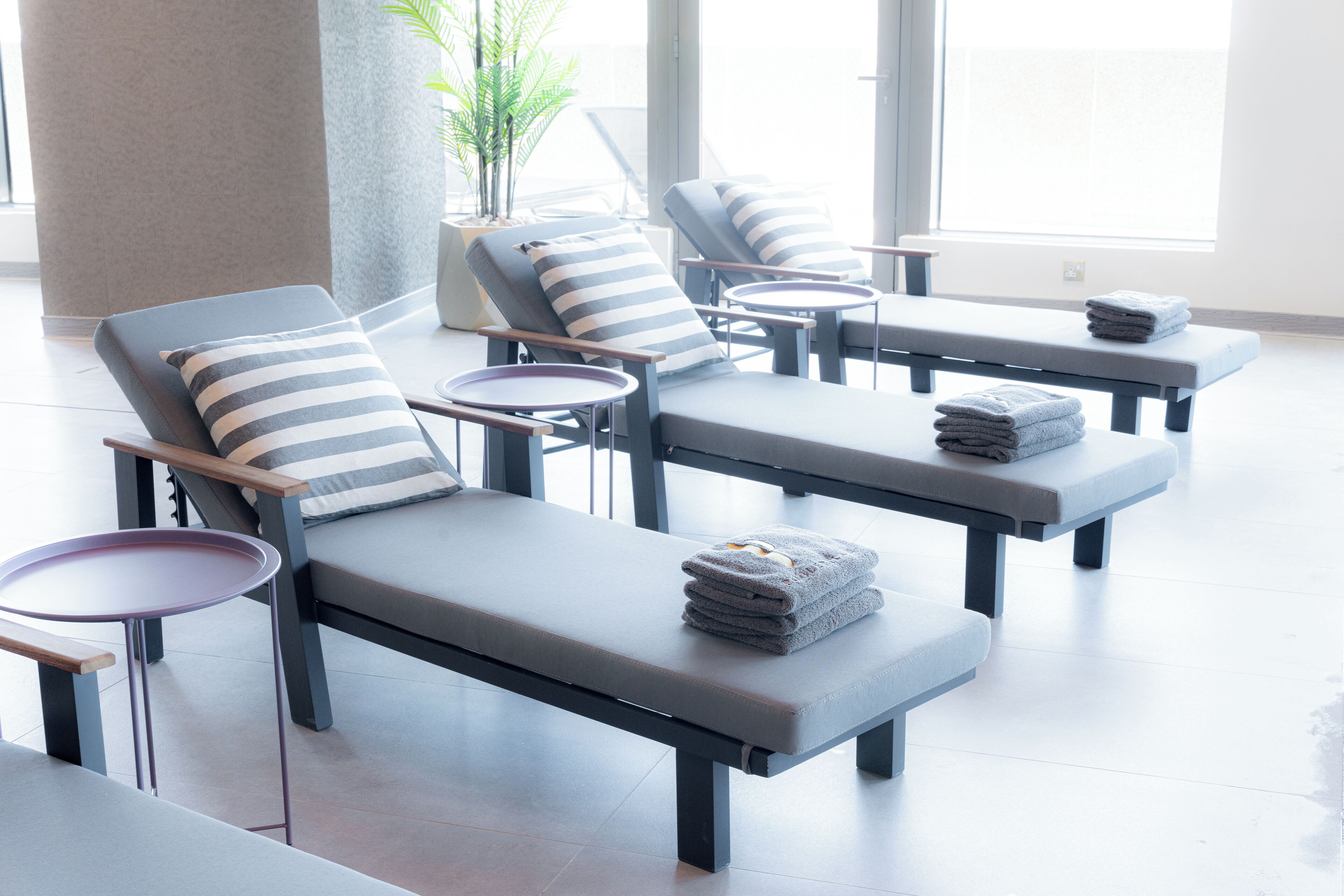 Un espace détente avec des fauteuils inclinables, de petites tables et des serviettes.