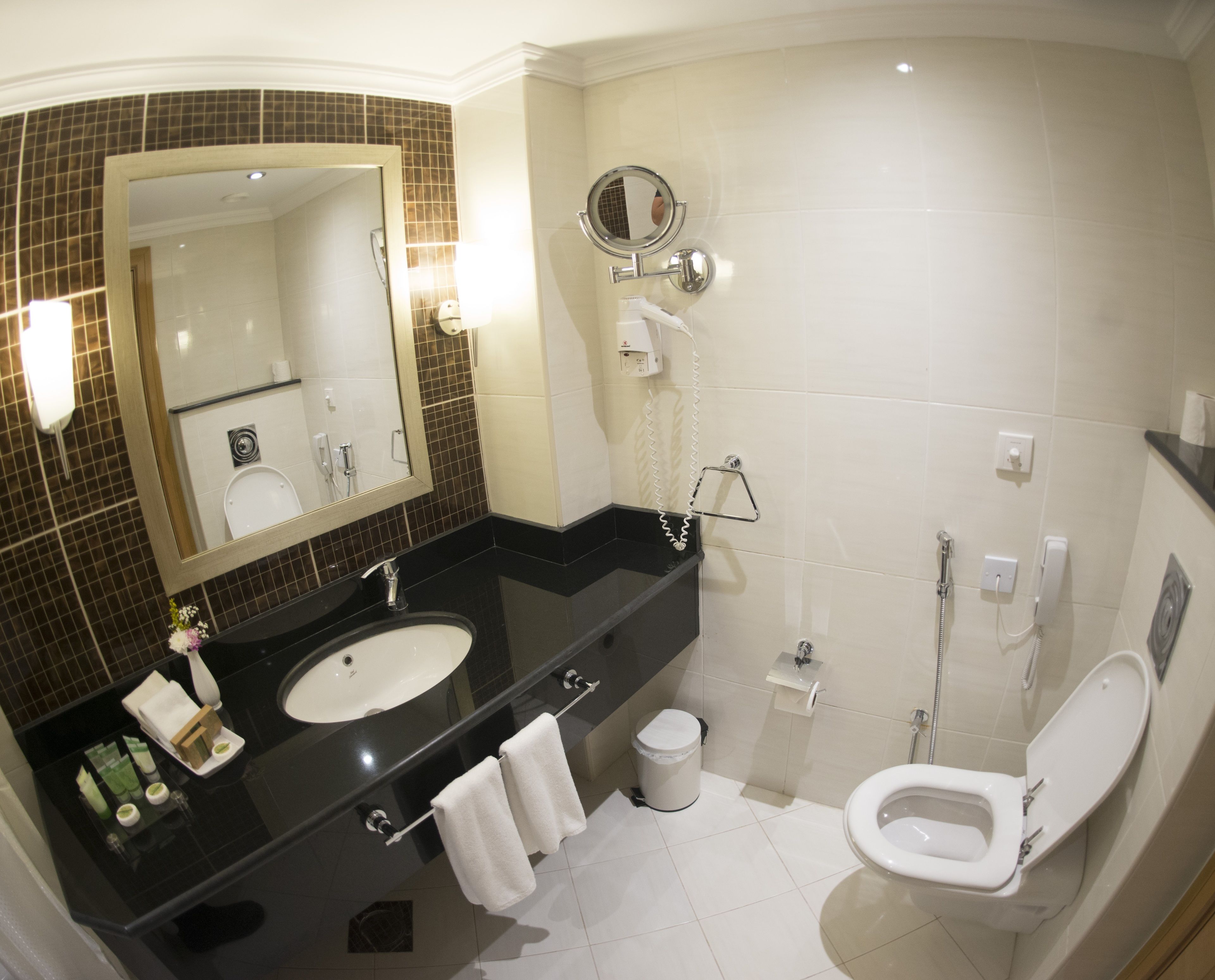 A modern bathroom with a black sink, two mirrors, a toilet, and a shower.