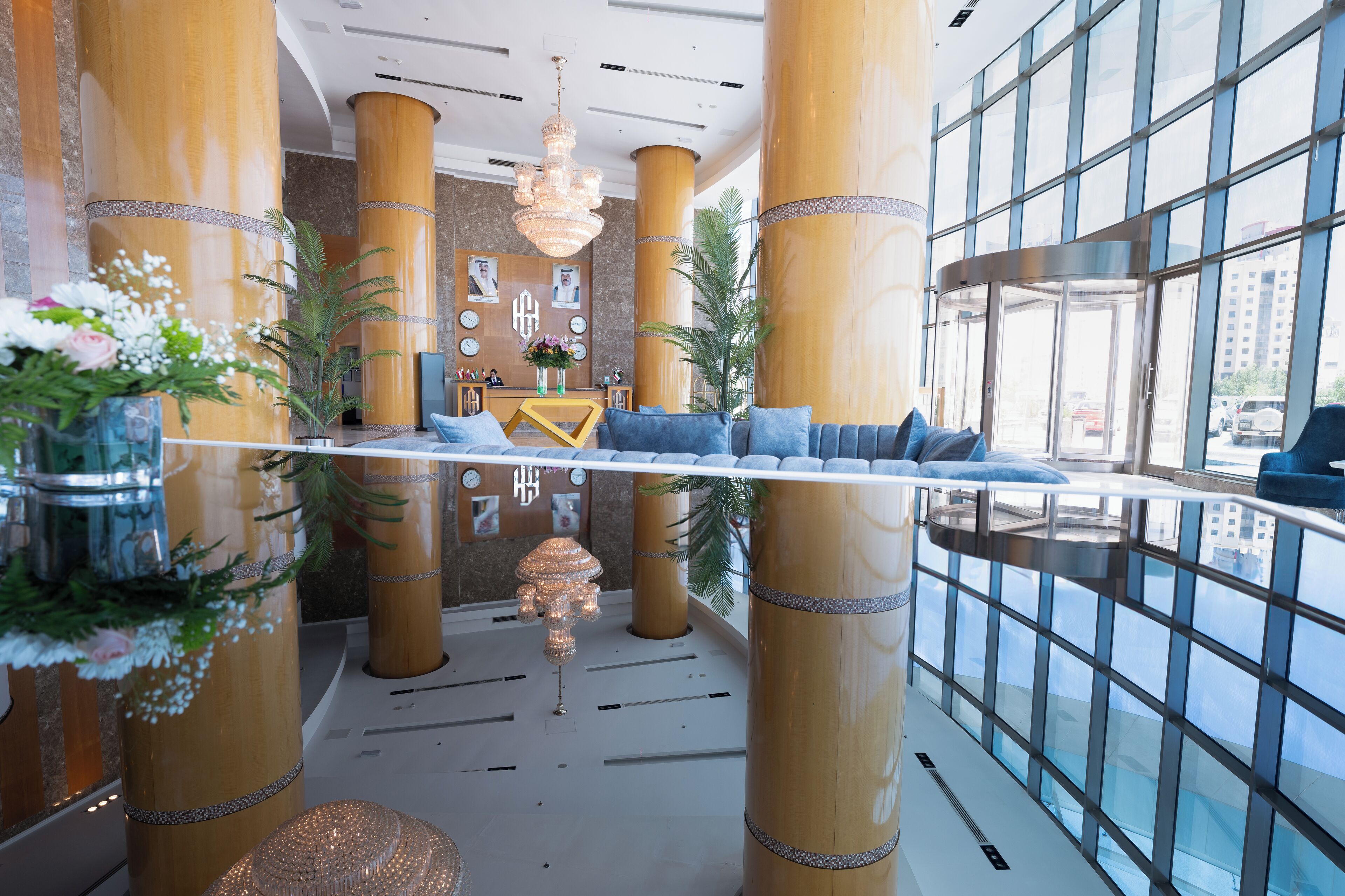 Eine Lobby mit großen, goldenen Säulen, einem Empfangstresen und einer Sitzecke mit blauen Kissen.