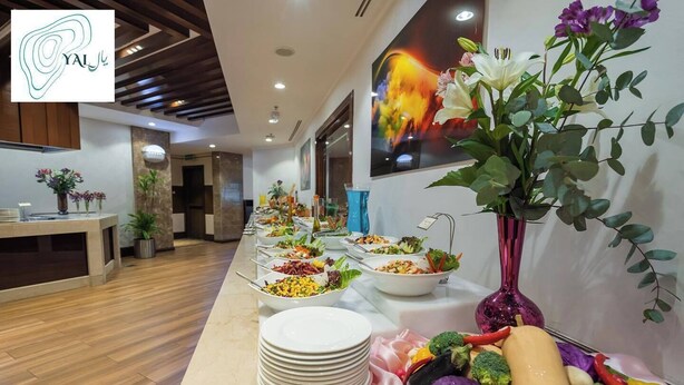A buffet setup with various dishes and a decorative vase. - Grand Hotel (Salmiya)