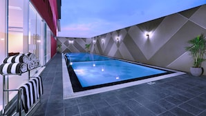 Une piscine intérieure à l’eau cristalline, entourée d’une architecture moderne aux motifs géométriques et dotée d’un éclairage d’ambiance.