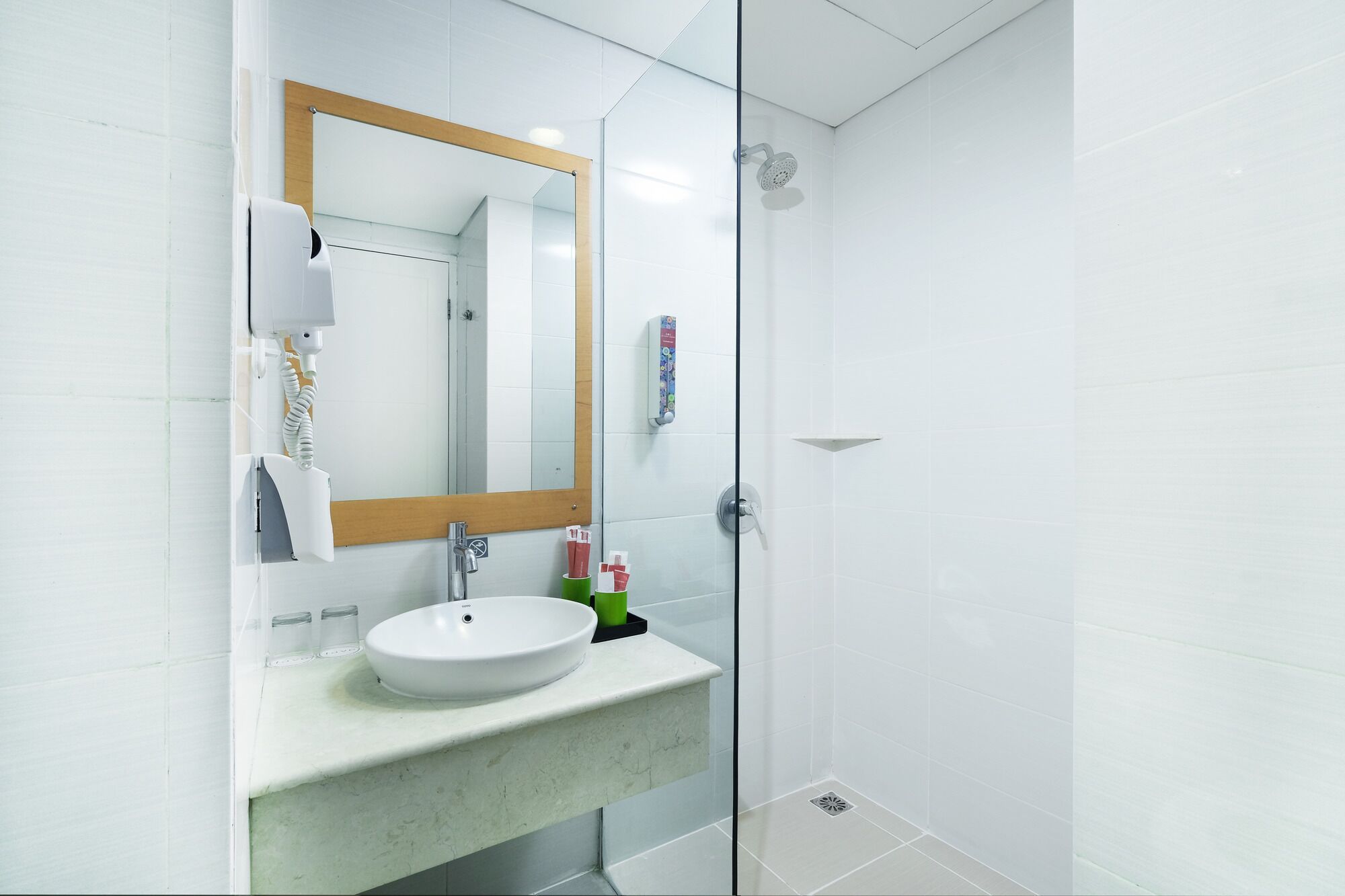 A modern bathroom with a glass shower enclosure, a white sink, and a large mirror with a wooden frame.