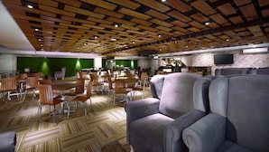 Un vaste espace dédié à la salle à manger, avec un plafond orné de panneaux en bois, des murs verts et un mobilier moderne.