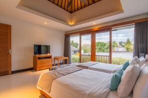 A modern hotel room with two beds, a TV, a wooden dresser, and large windows offering a view of the outdoors.