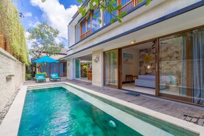 A modern house with a swimming pool, large sliding glass doors, and a wooden deck.