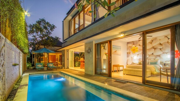 Una casa moderna con piscina, grandes puertas de vidrio que dan a una sala de estar y un balcón con mobiliario exterior.