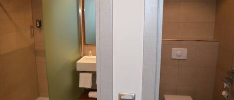 A bathroom with a glass shower door, a toilet, and a sink with a towel rack.