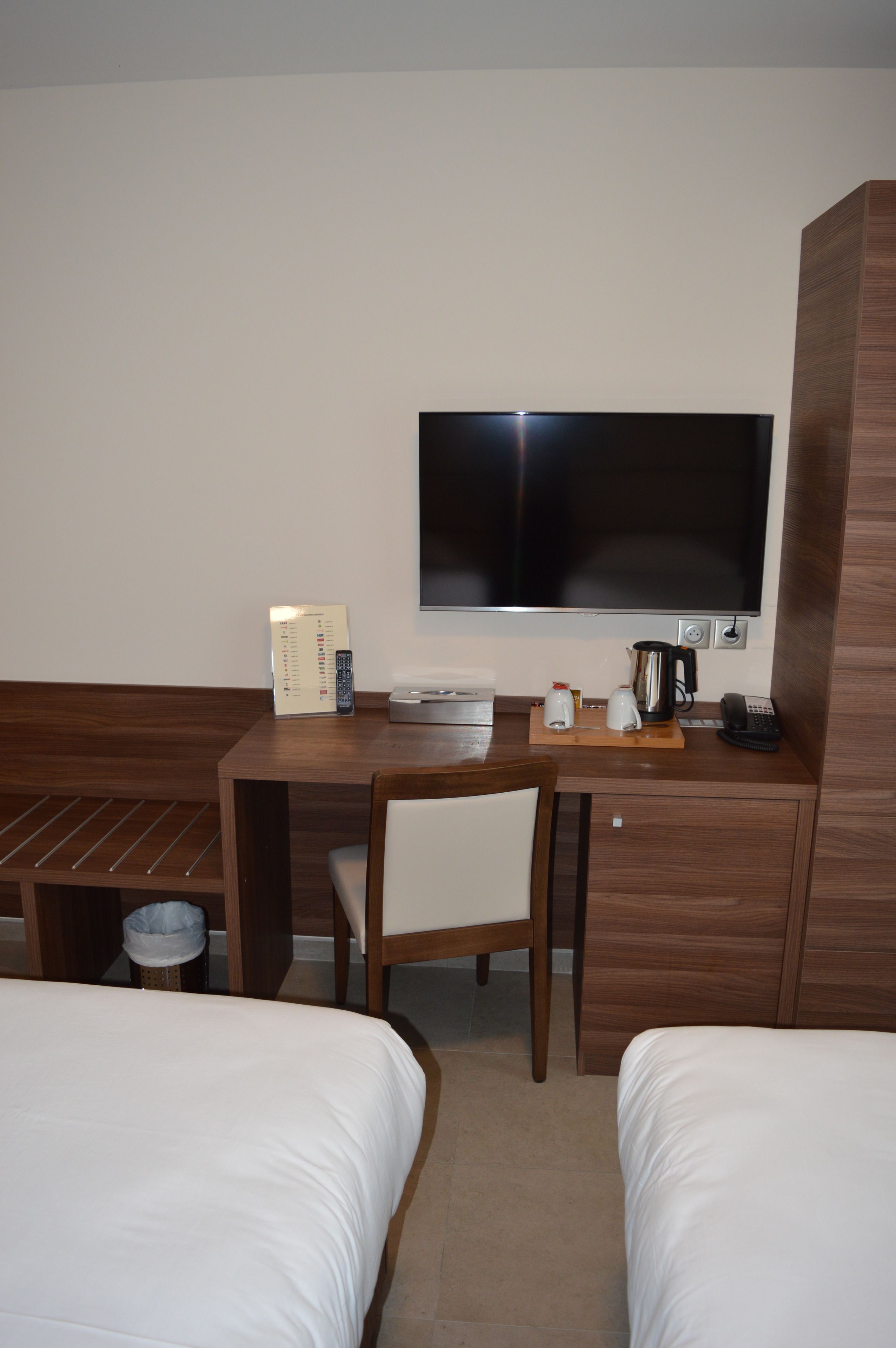Une chambre d’hôtel équipée d’un lit, d’un bureau avec un téléviseur à écran plat, d’une machine à café et d’un téléphone.