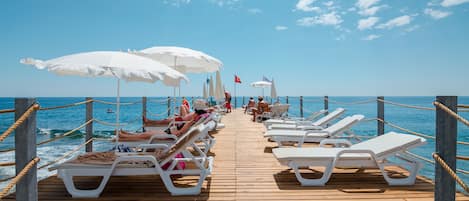 Een privéstrand, ligstoelen aan het strand, parasols, strandlakens