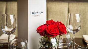 A table setting with a menu box labeled "Lakeview bar restaurant" and a vase with red roses.
