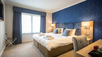 A modern hotel room with a large bed, a desk, and a window with curtains.