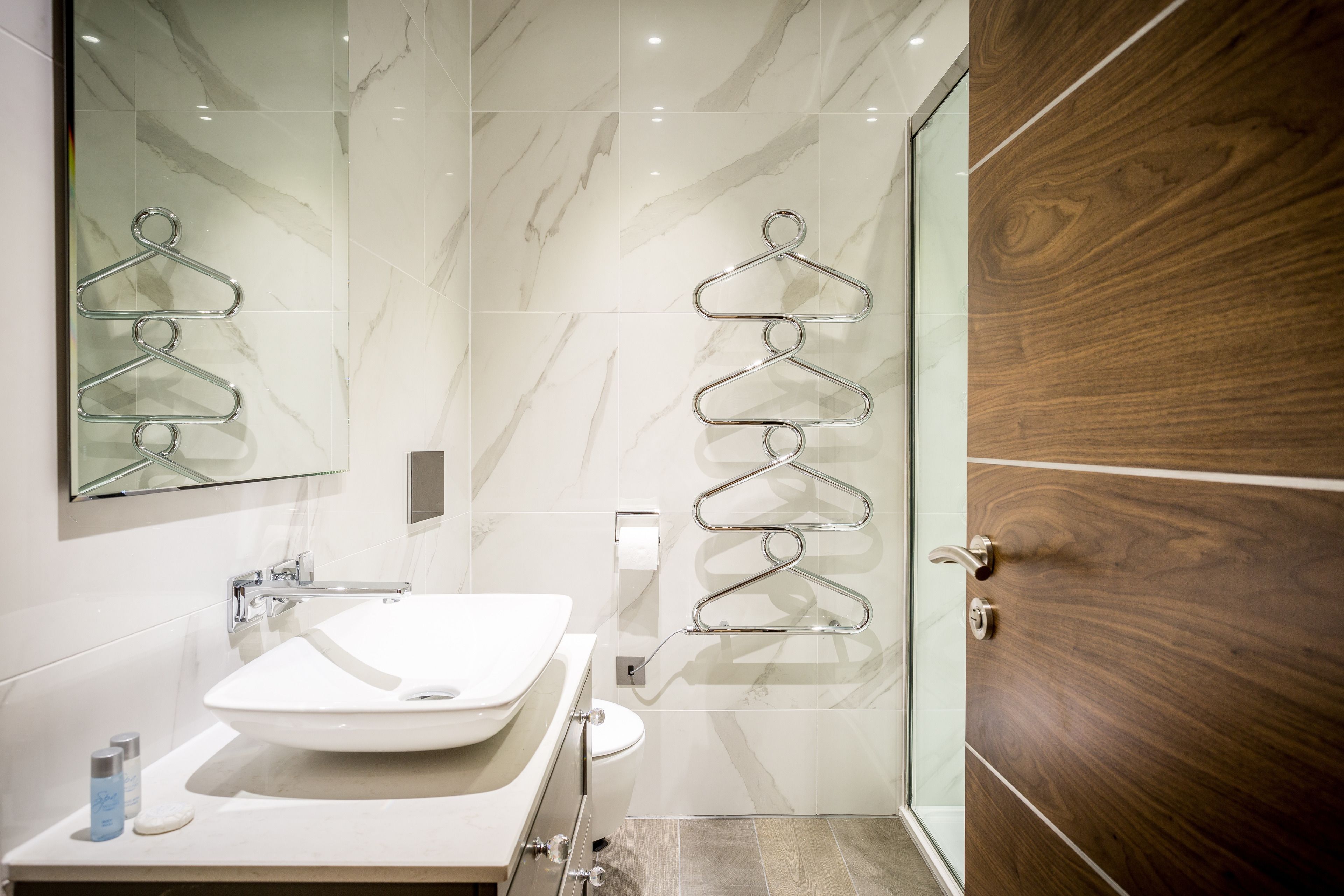 A modern bathroom with a white sink, a glass shower enclosure, and wooden paneling.