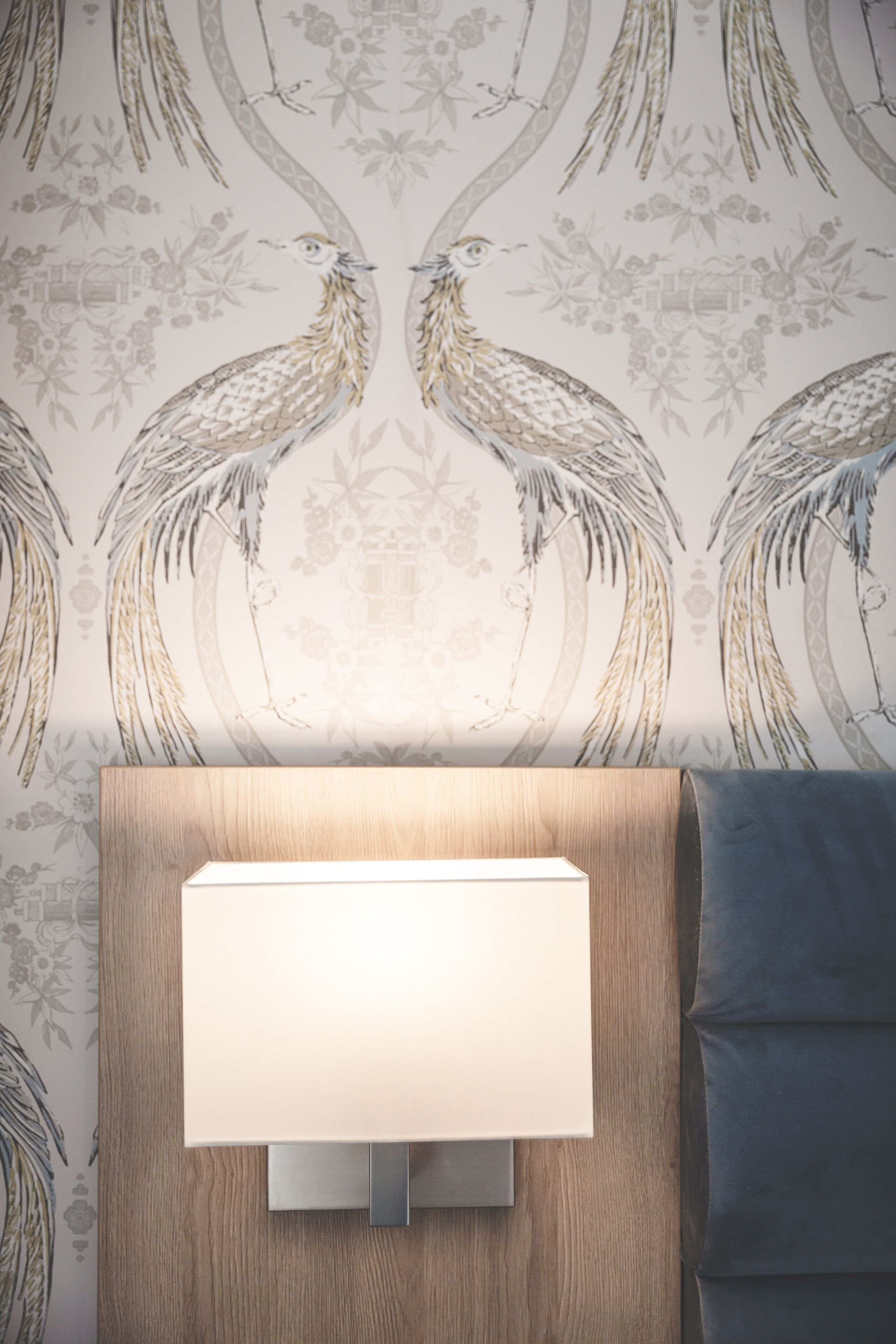 A wall with a decorative wallpaper featuring birds and floral patterns.