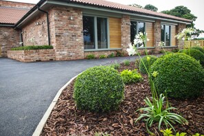 A brick house with a tiled roof, large windows, and a well-maintained garden with shrubs and flowers. - The Nottinghamshire Hotel and Golf Club (Nottingham)