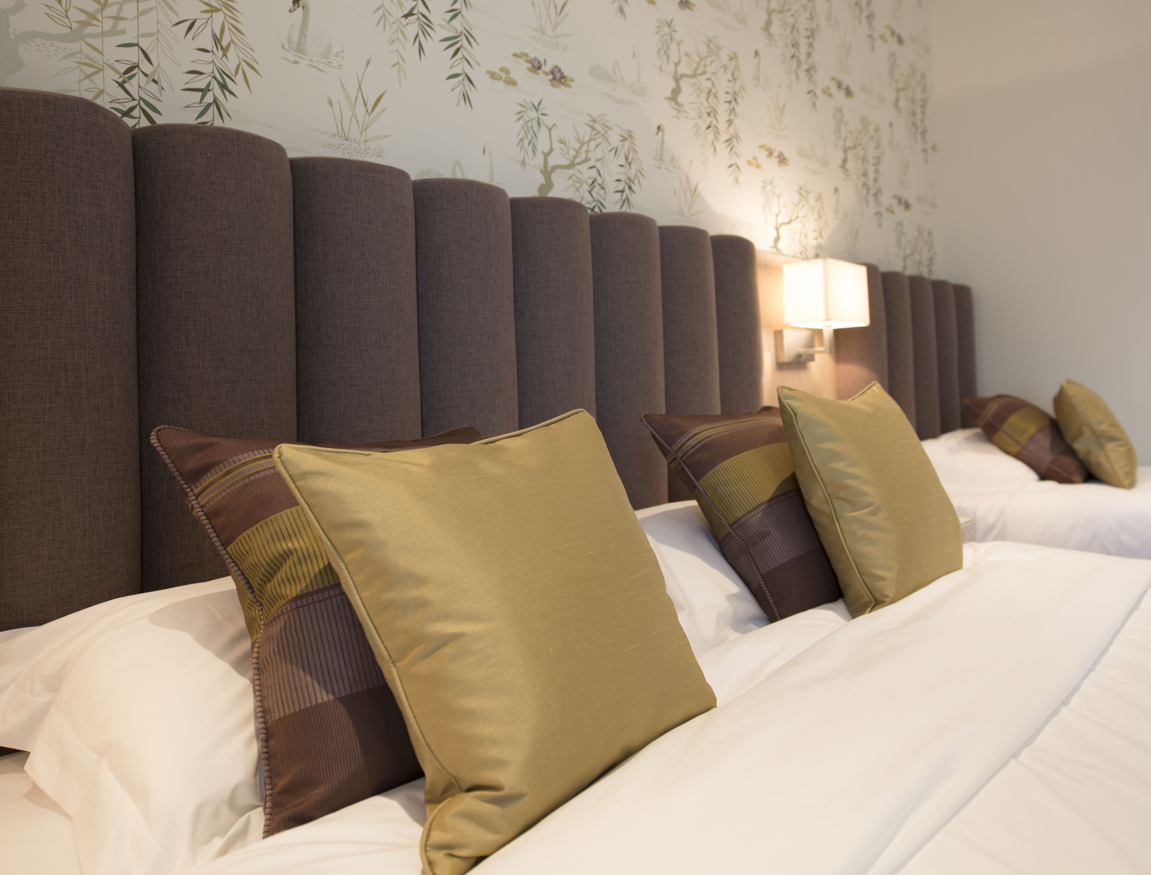 Une chambre d’hôtel avec un grand lit, plusieurs oreillers et une tête de lit dotée de panneaux verticaux.