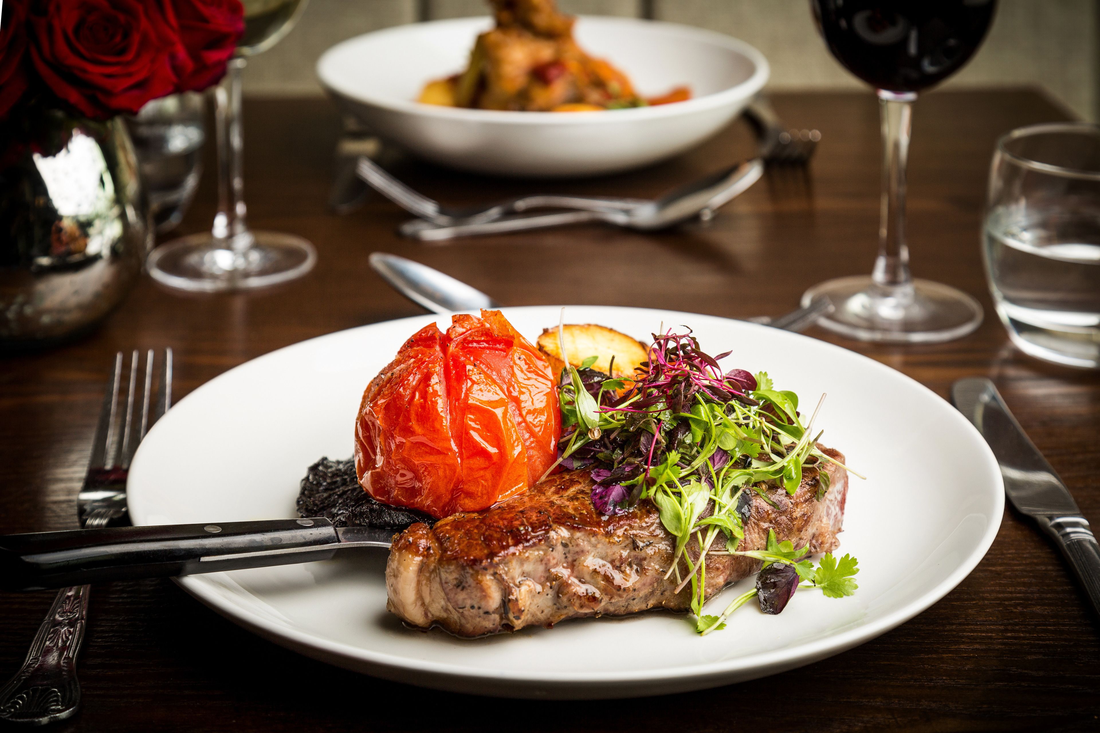 A dining table with a plate of food, a fork, a knife, and a glass of wine.