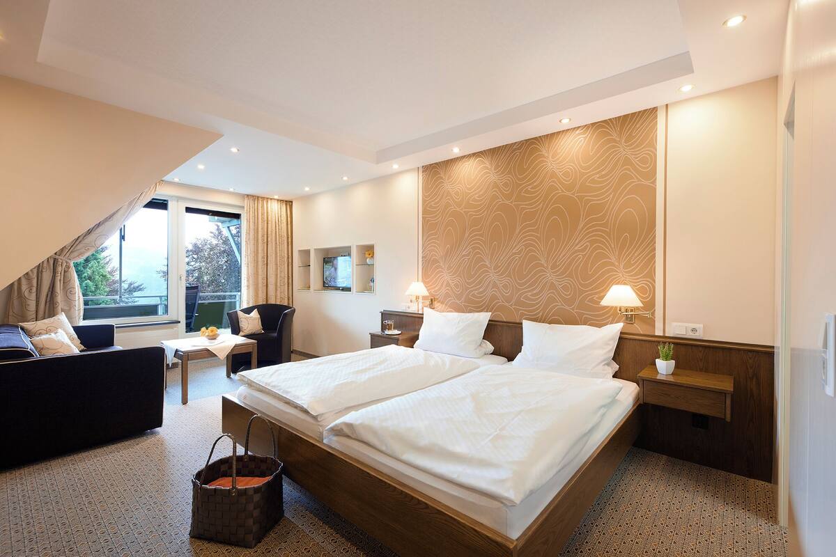 Una habitación de hotel con una cama grande, un sofá, un televisor y un escritorio.