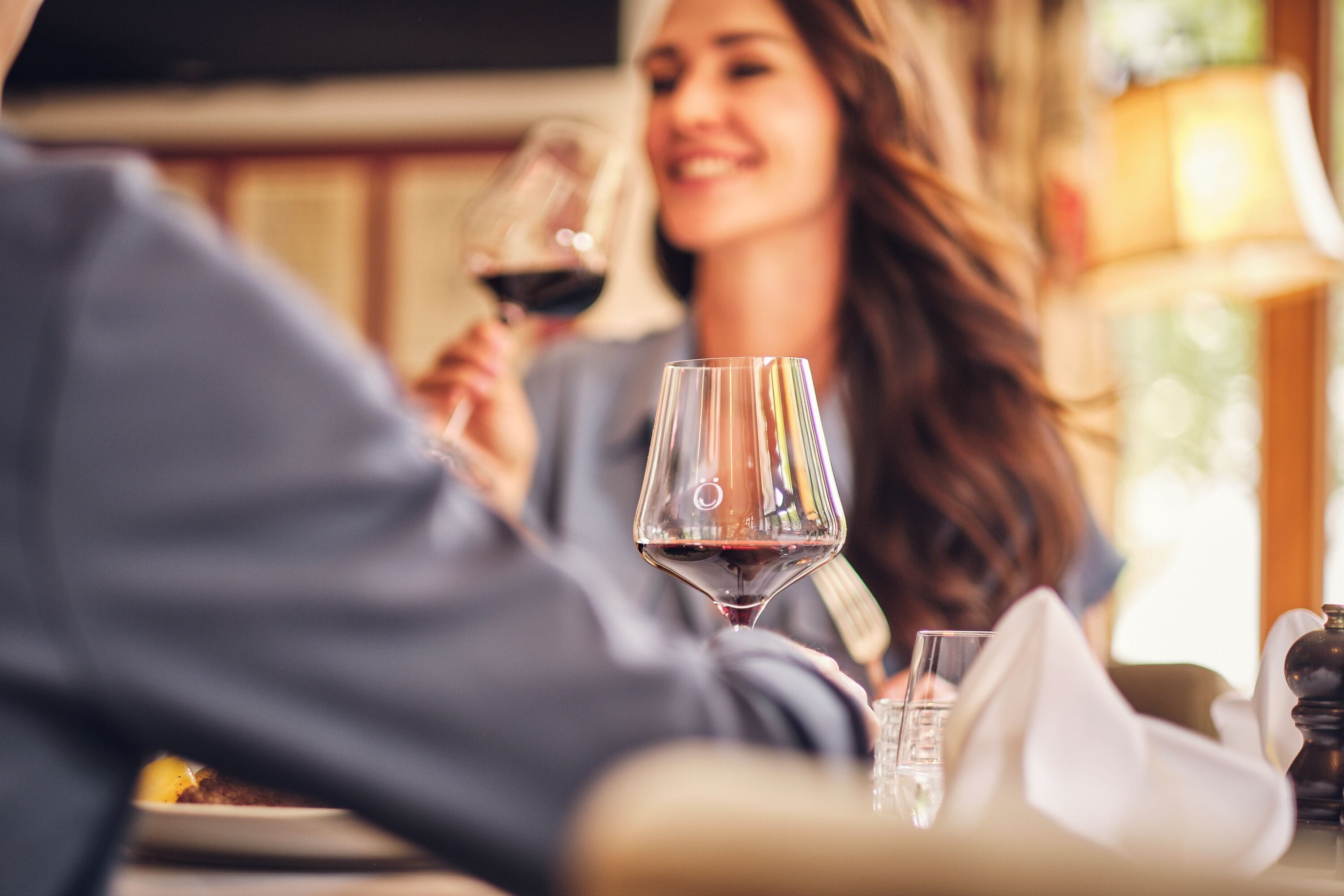 A dining table with a wine glass and a napkin.