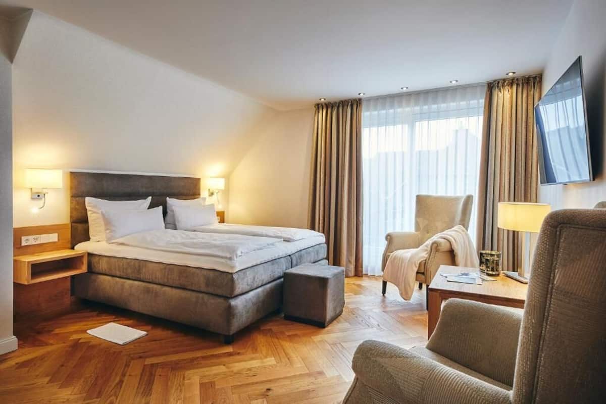 Una habitación de hotel con cama, una silla, televisor y escritorio.