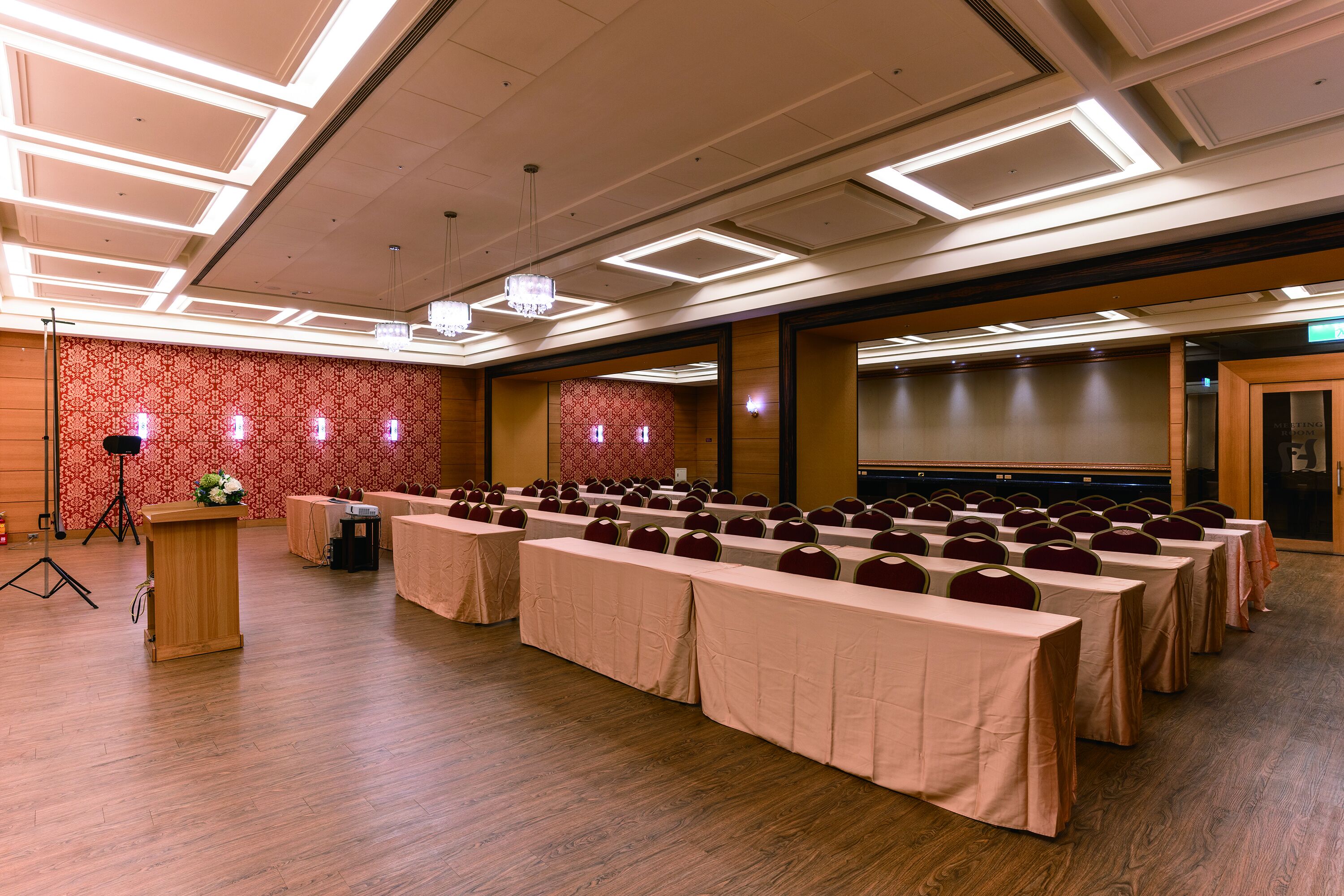 Un salón de conferencias con mesas dispuestas en filas, un atril y un escenario.