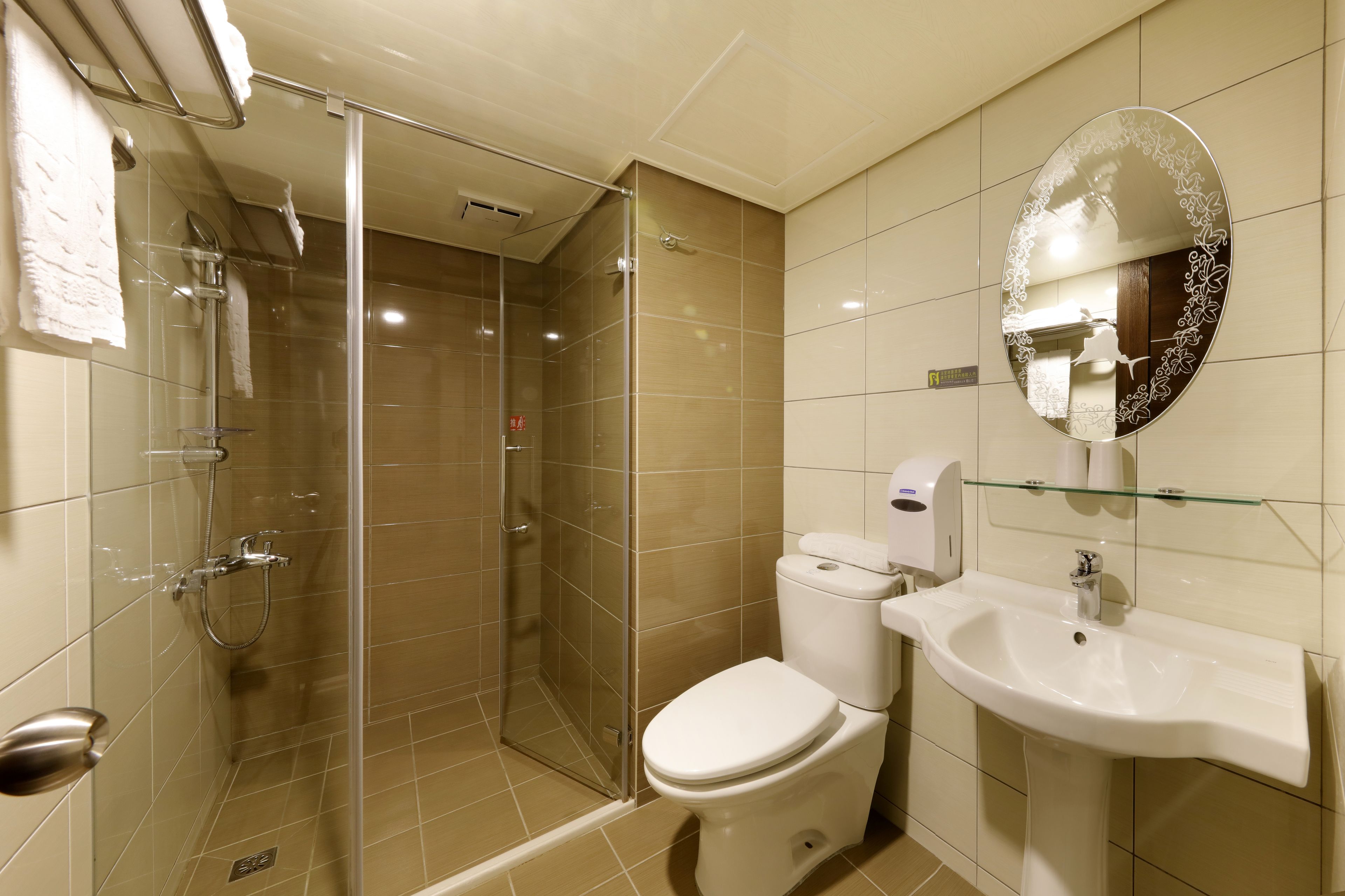A modern bathroom with a glass-enclosed shower, a white toilet, and a sink with a glass shelf above it.