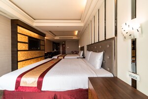 Habitación de hotel con una cama grande, televisor, mesita de noche de madera y lámpara fijada a la pared.