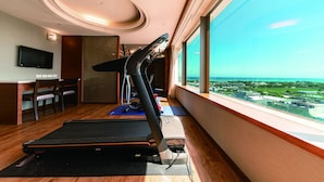 A room with a treadmill, exercise mats, a TV, and a dining area with chairs and a table. - Fish Hotel - Taitung (Taitung)