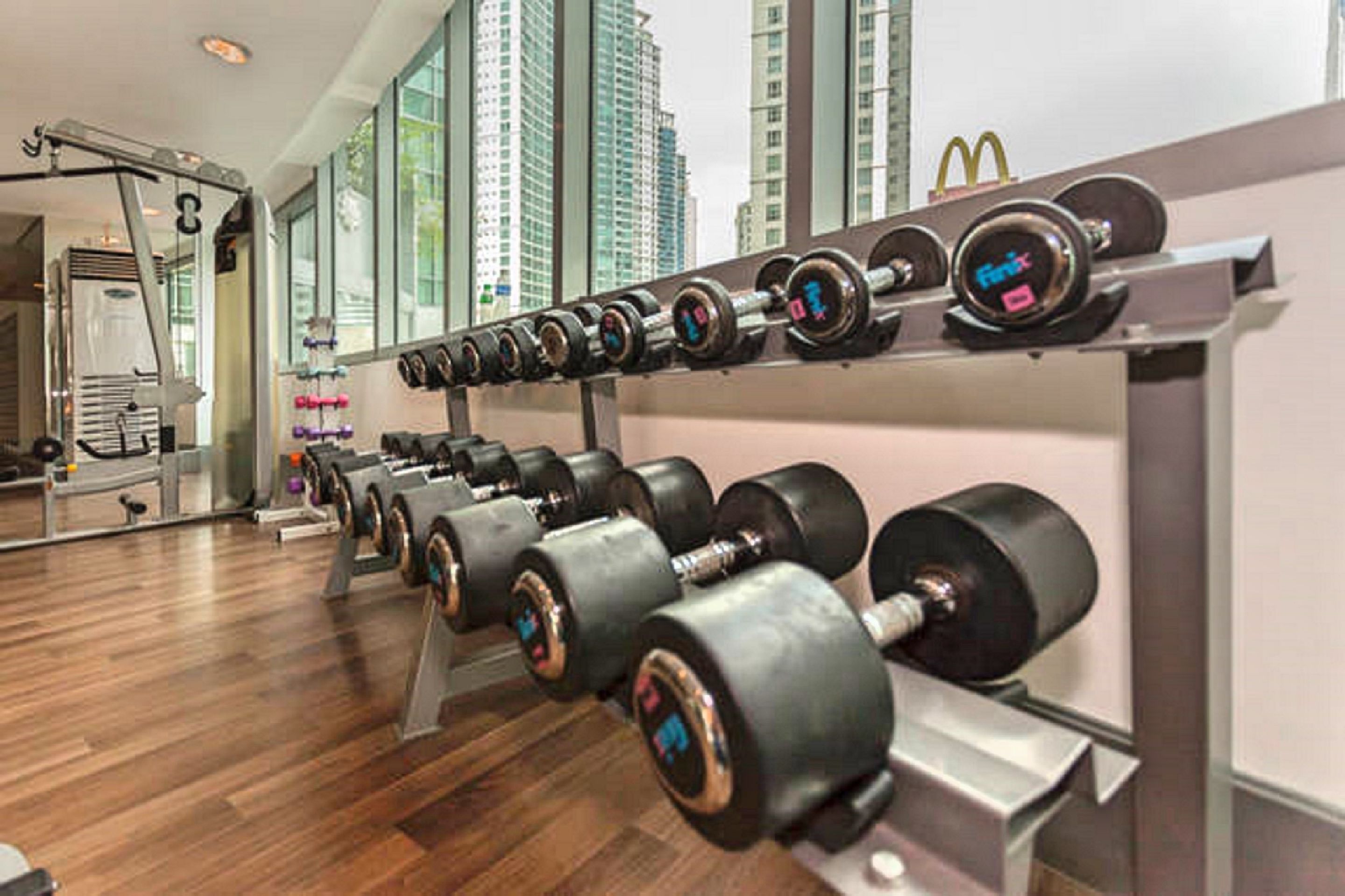 Un gimnasio con filas de mancuernas y un soporte para pesas.