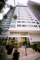 Un edificio moderno con fachada de vidrio, varios pisos y una escalera que conduce a la entrada.