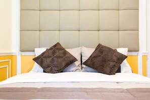 A bed with a tufted headboard, two patterned pillows, and a white bedspread. - Avant Apartments At The Fort (Taguig)