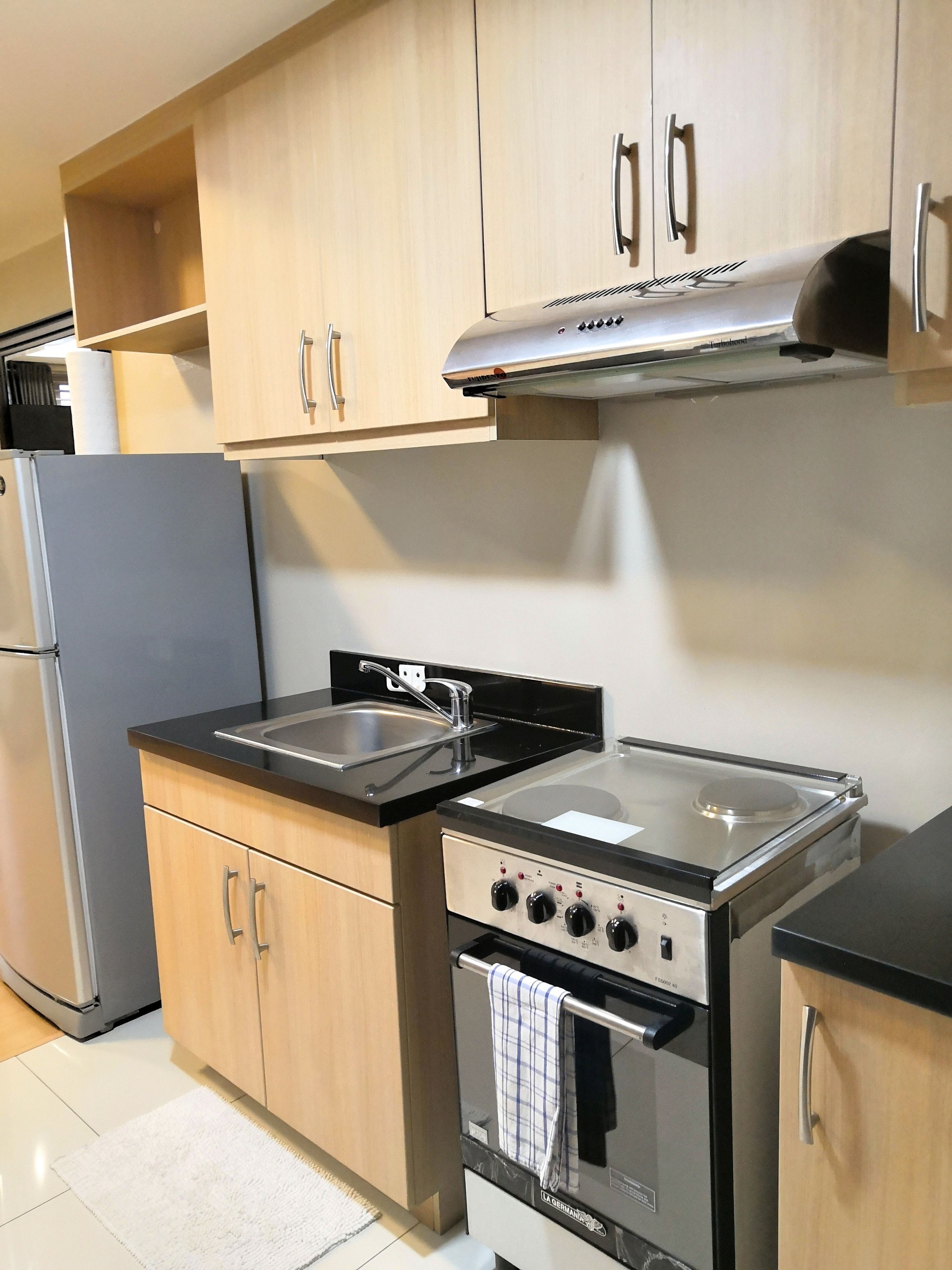 A modern kitchen with stainless steel appliances, wooden cabinets, and a black countertop.