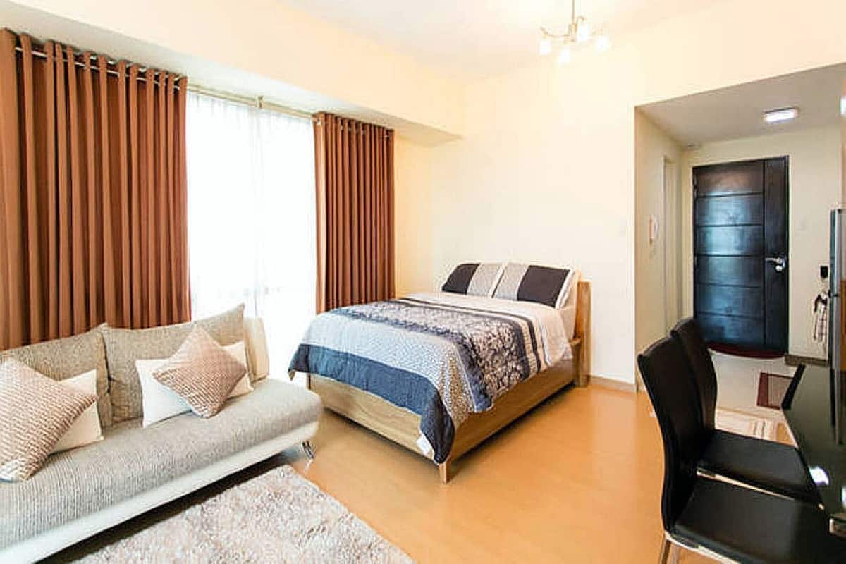 A bedroom with a bed, a sofa, a chair, and a desk.