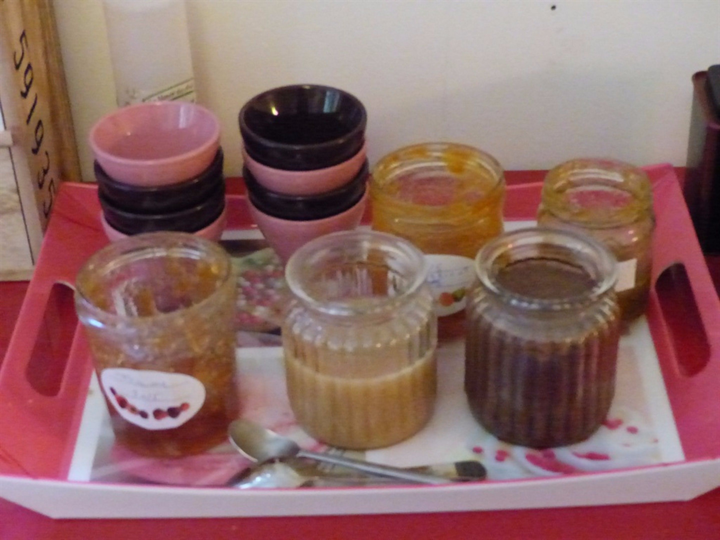A tray with various jars and bowls, some with lids and others open, on a pink tray.