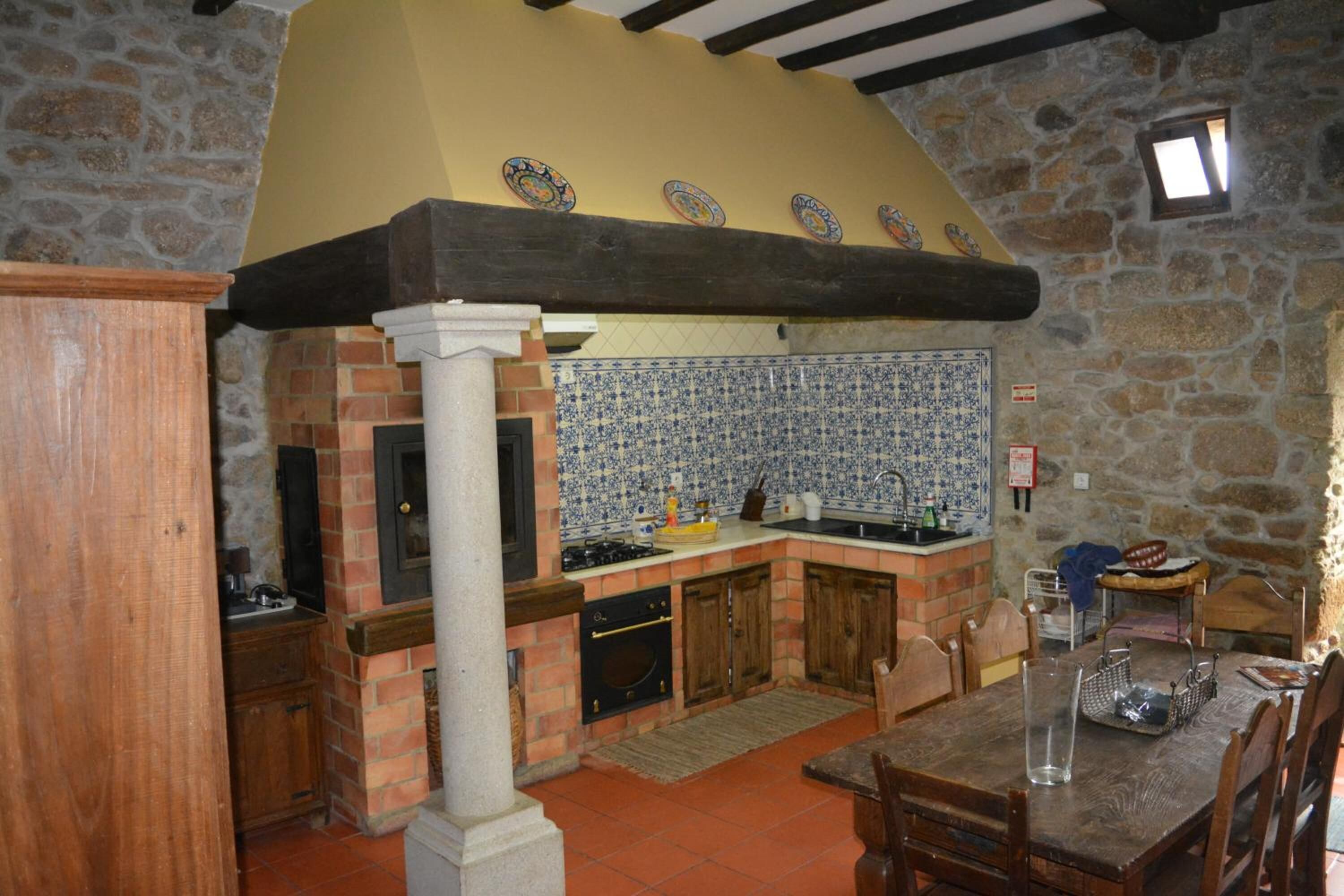 A rustic kitchen with a stone wall, a tiled backsplash, and wooden cabinets.