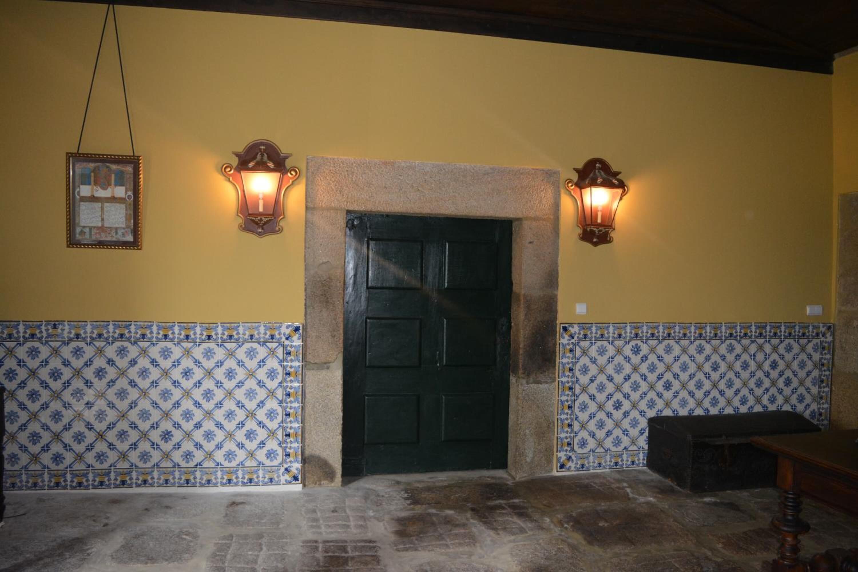 A room with a tiled wall, a stone fireplace, and two wall-mounted lights.