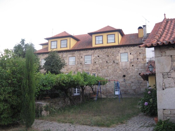 A stone building with a yellow facade and red-tiled roof.