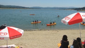 A beach with kayaks on the water and umbrellas on the sand.