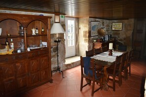 A rustic dining area with a wooden table and chairs, a cabinet with glassware, and a lamp. - Solar dos Correia Alves (Moimenta da Beira)