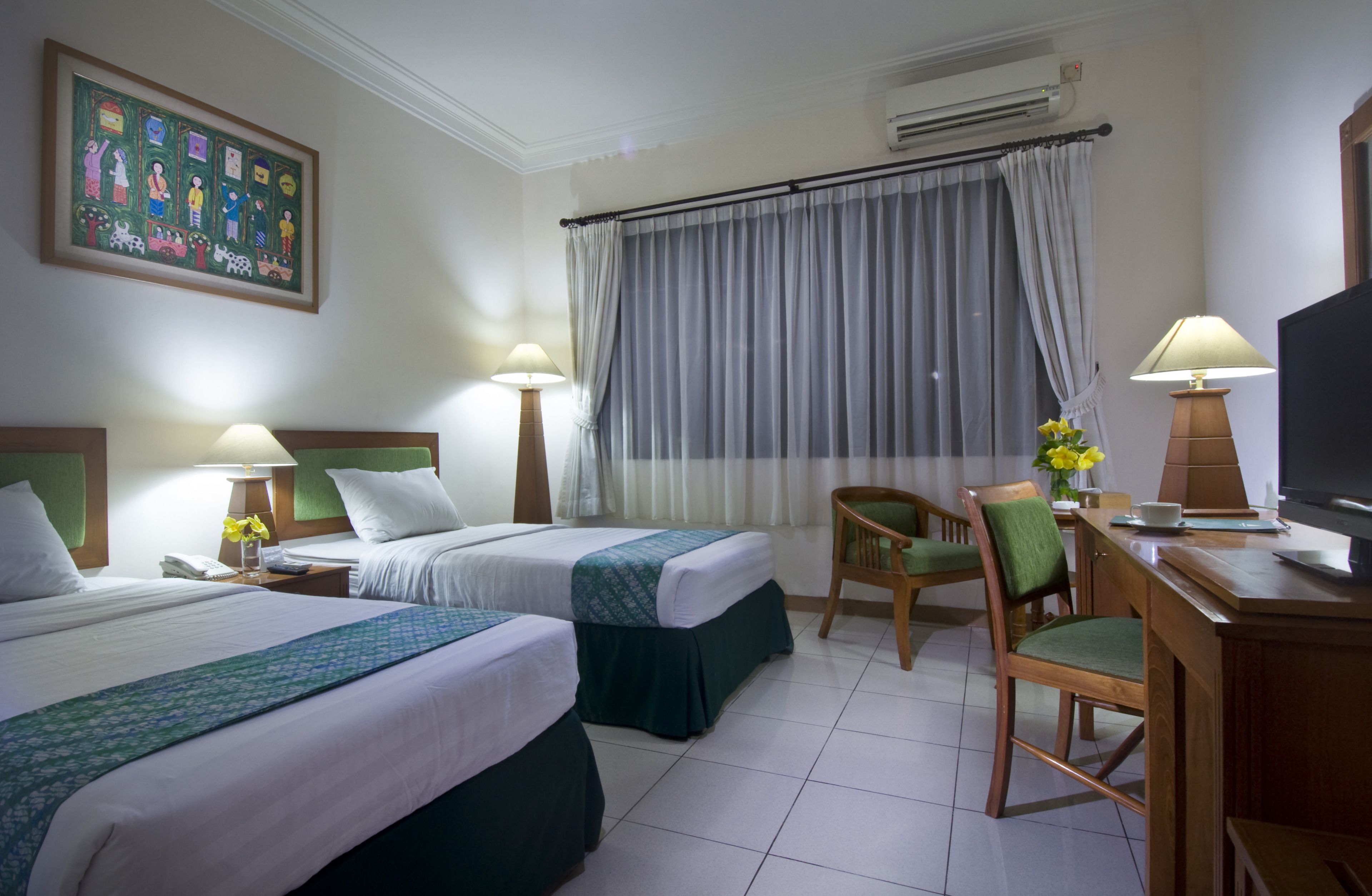 Habitación de hotel con dos camas, un escritorio, una silla, un televisor y un cuadro en la pared.