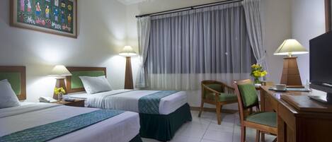 Habitación de hotel con dos camas, un escritorio, una silla, un televisor y un cuadro en la pared.