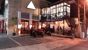 A two-story building with a ground-floor restaurant and upper-floor rooms. Motorcycles are parked in front, and a staircase leads to the upper level. - Griya Sentana Hotel Jogjakarta (Yogyakarta)