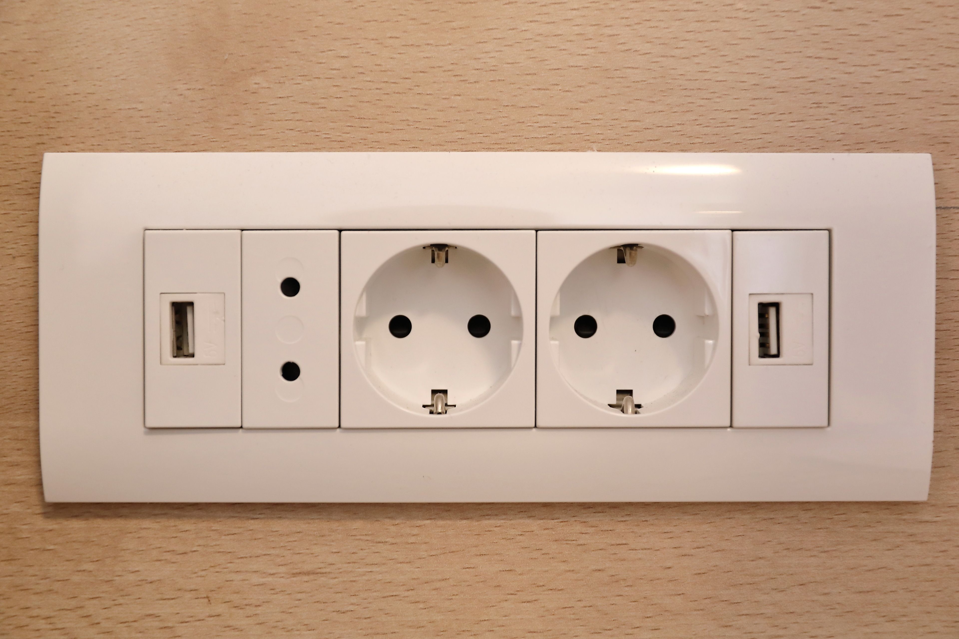 Un enchufe blanco con tres tomas de corriente y dos puertos USB.